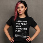 Young woman wearing a black t-shirt that says “I Asked My Dog About Your Marketing Plan,” featuring a minimalist dog graphic and Stark Create branding